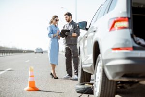 Worker with woman near the broken car on the highway